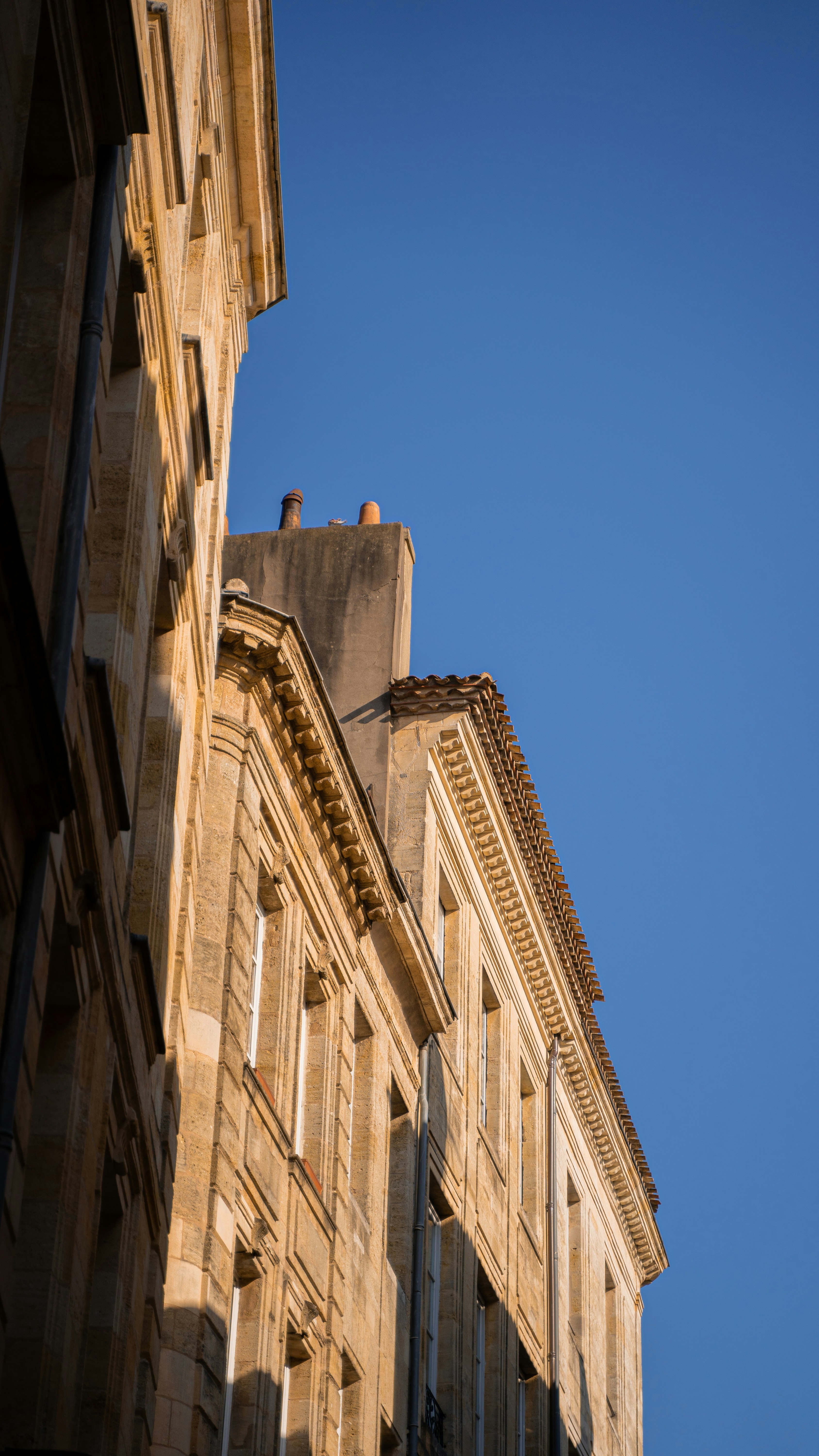 low angle photography of beige concrete building under blue sky during daytime